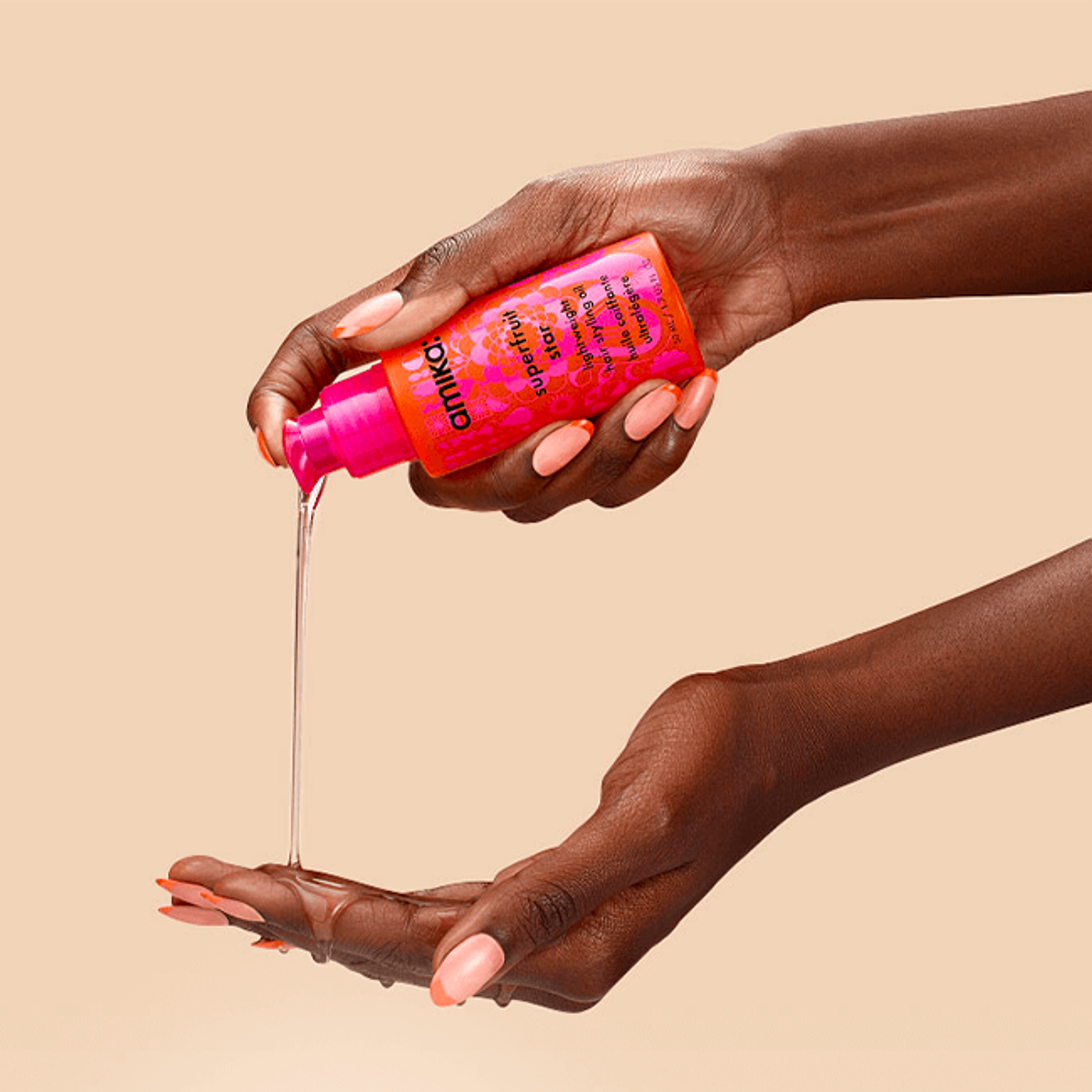 two hands pouring amika superfruit star oil against a cream background