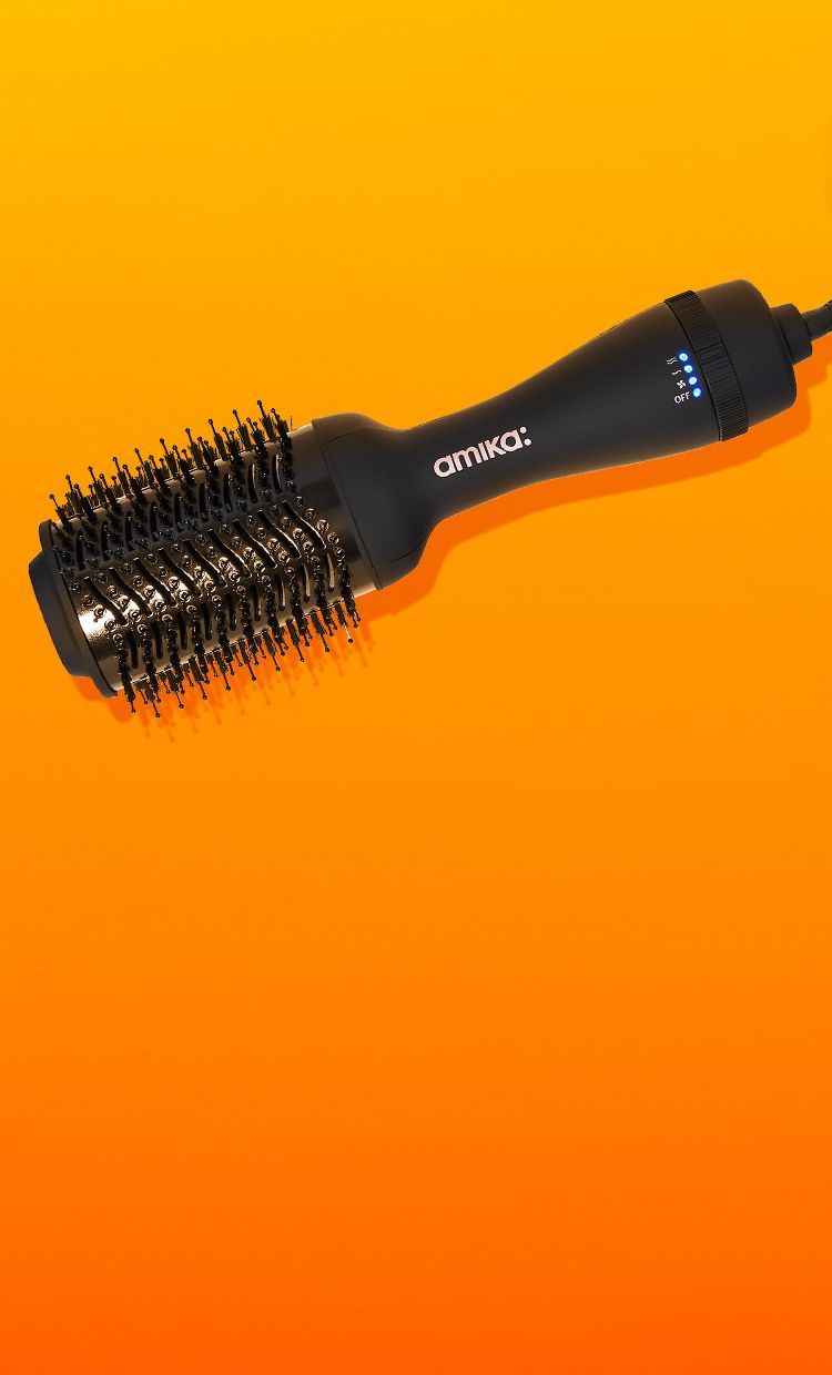 amika hair blow dryer brush 2.0 on an orange and yellow background