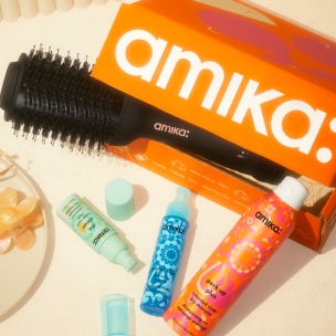 amika mailer box shown with hair blow dryer brush and product assortment on cream counter top