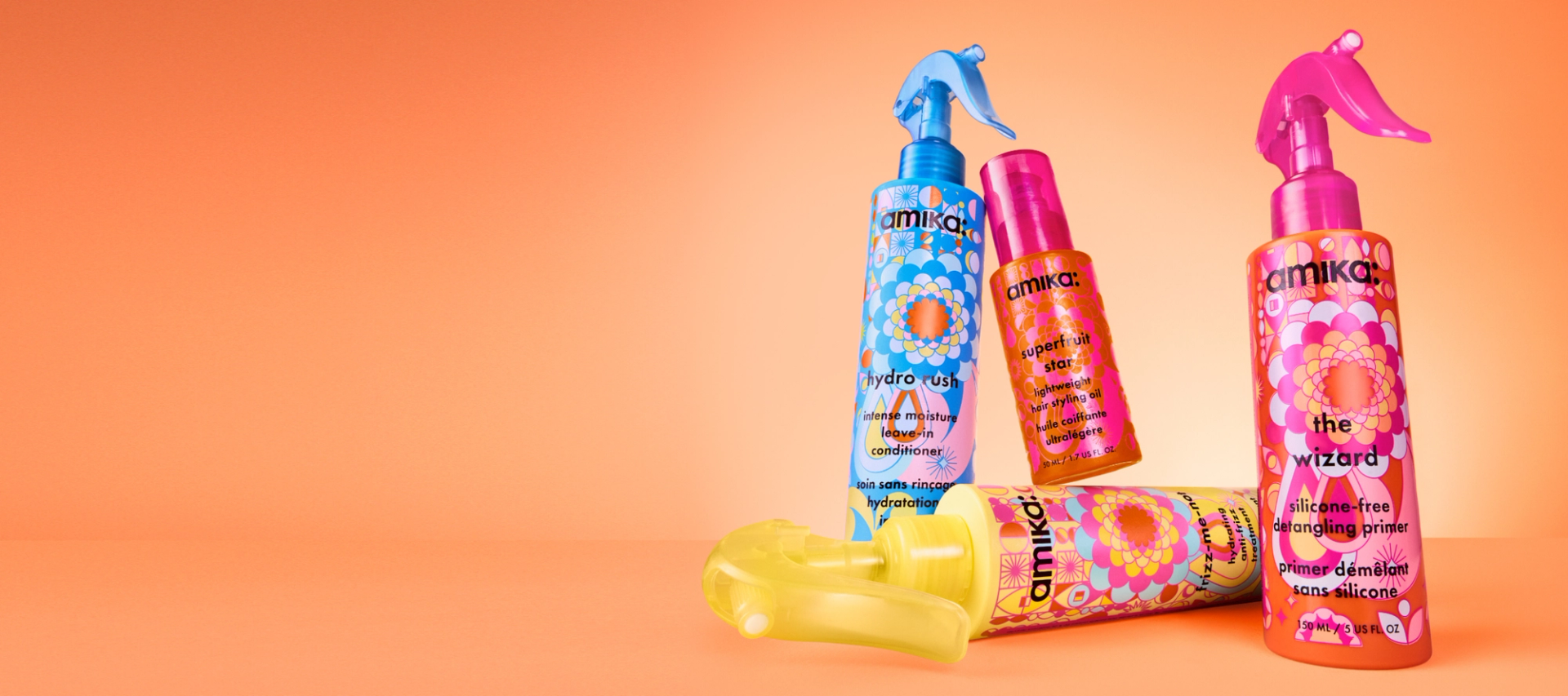 amika treatments: hydro rush leave in conditioner, superfruit star oil, the wizard silicone-free detangling primer and frizz-me-not anti-frizz treatment against an orange backdrop