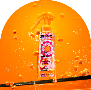 amika the wizard detangling primer against a n orange backgound with splashes of water and sea buckthorn berries floating