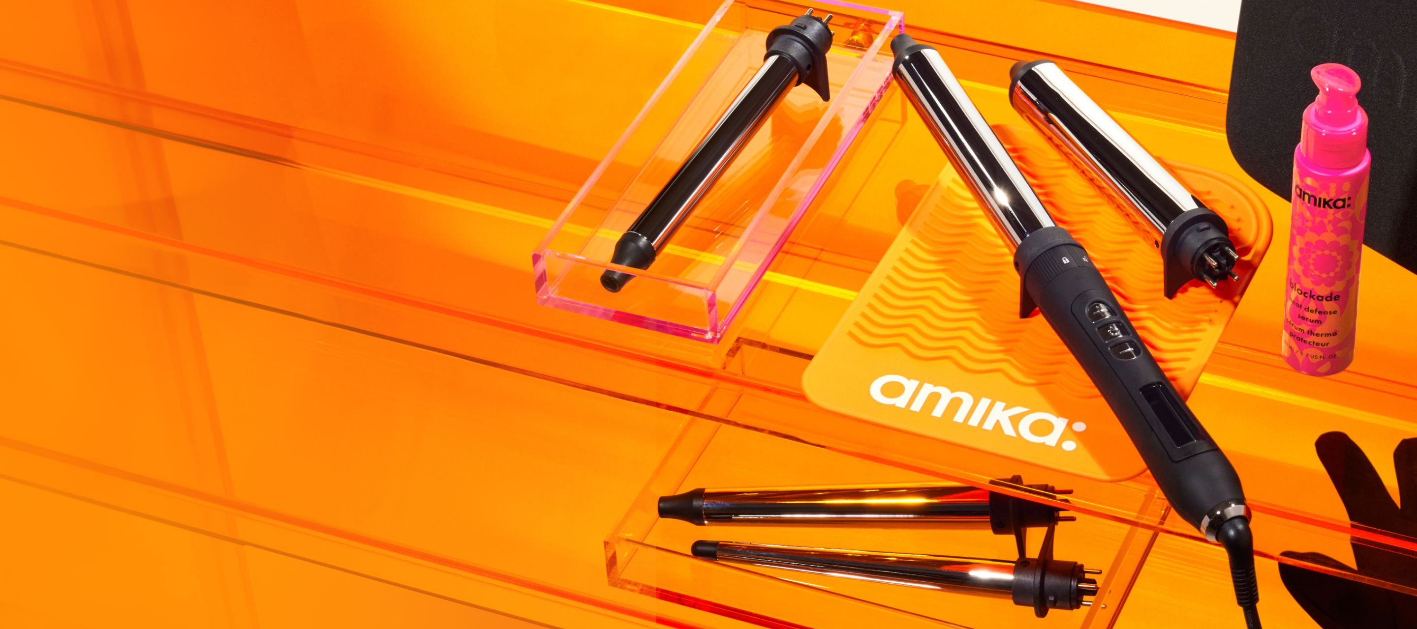 amika's chameleon curling iron on an orange table