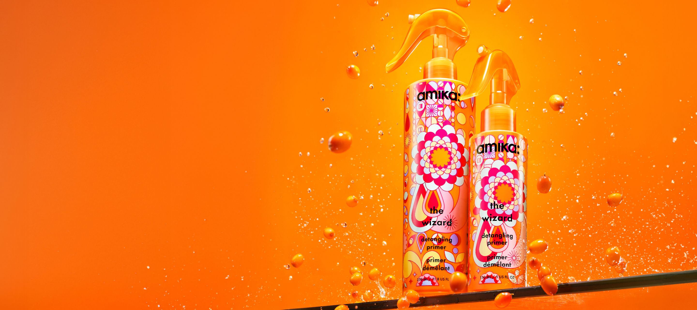 two bottles of the wizard detangling primer on a shelf with an orange background and seabuckthorn surrounding the bottles