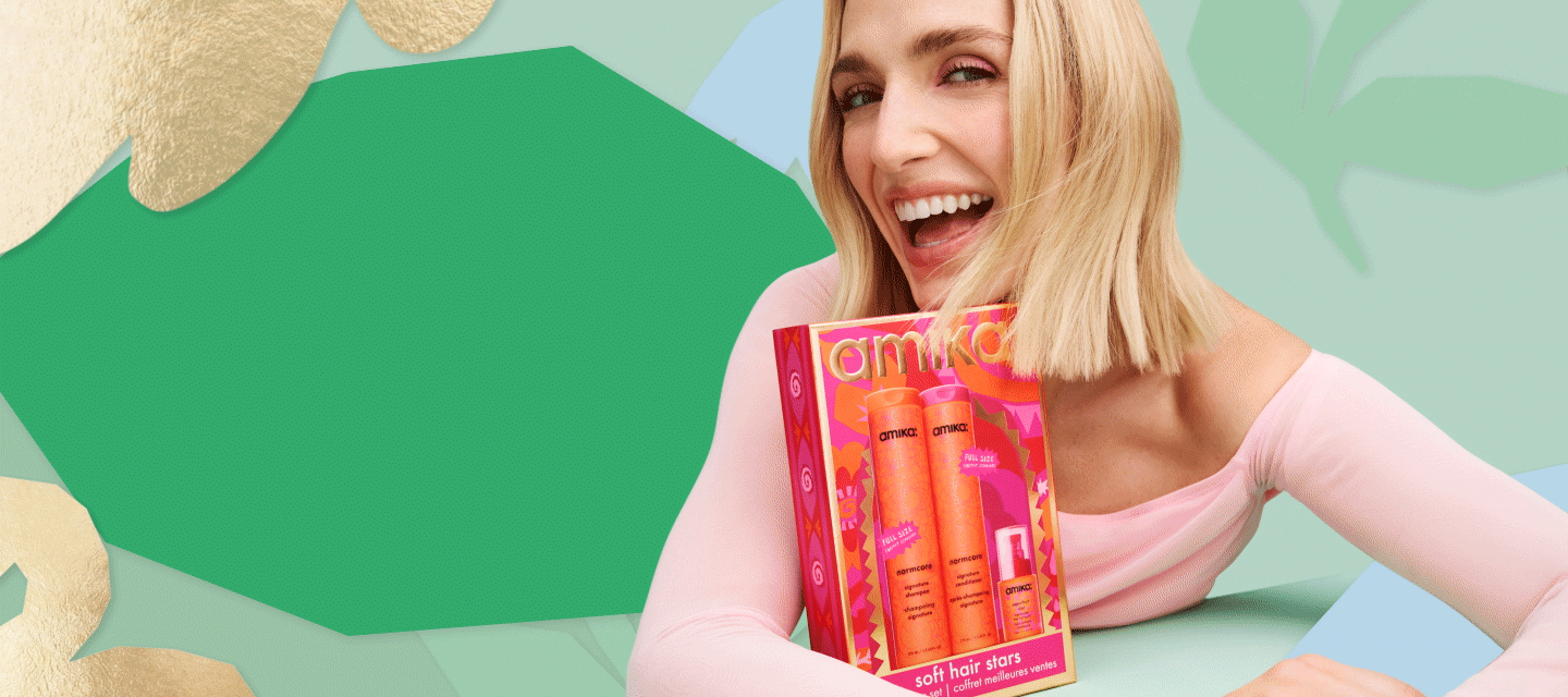 a blonde model holds 'soft hair stars' an amika holiday hair gift box set against a light green background and a larger, darker green leaf shape next to her