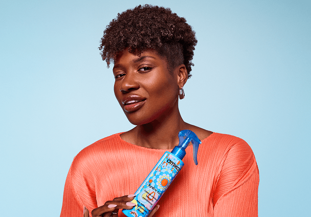 a model holds a bottle of amika hydro rush leave-in conditioner