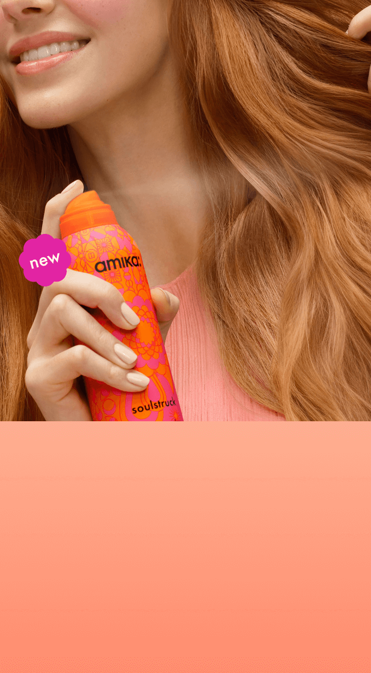 closeup image of a person spraying amika soulstruck mask on their wavy, red hair