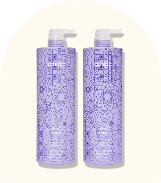 image of supersized blonde shampoo and conditioner against a beige background.