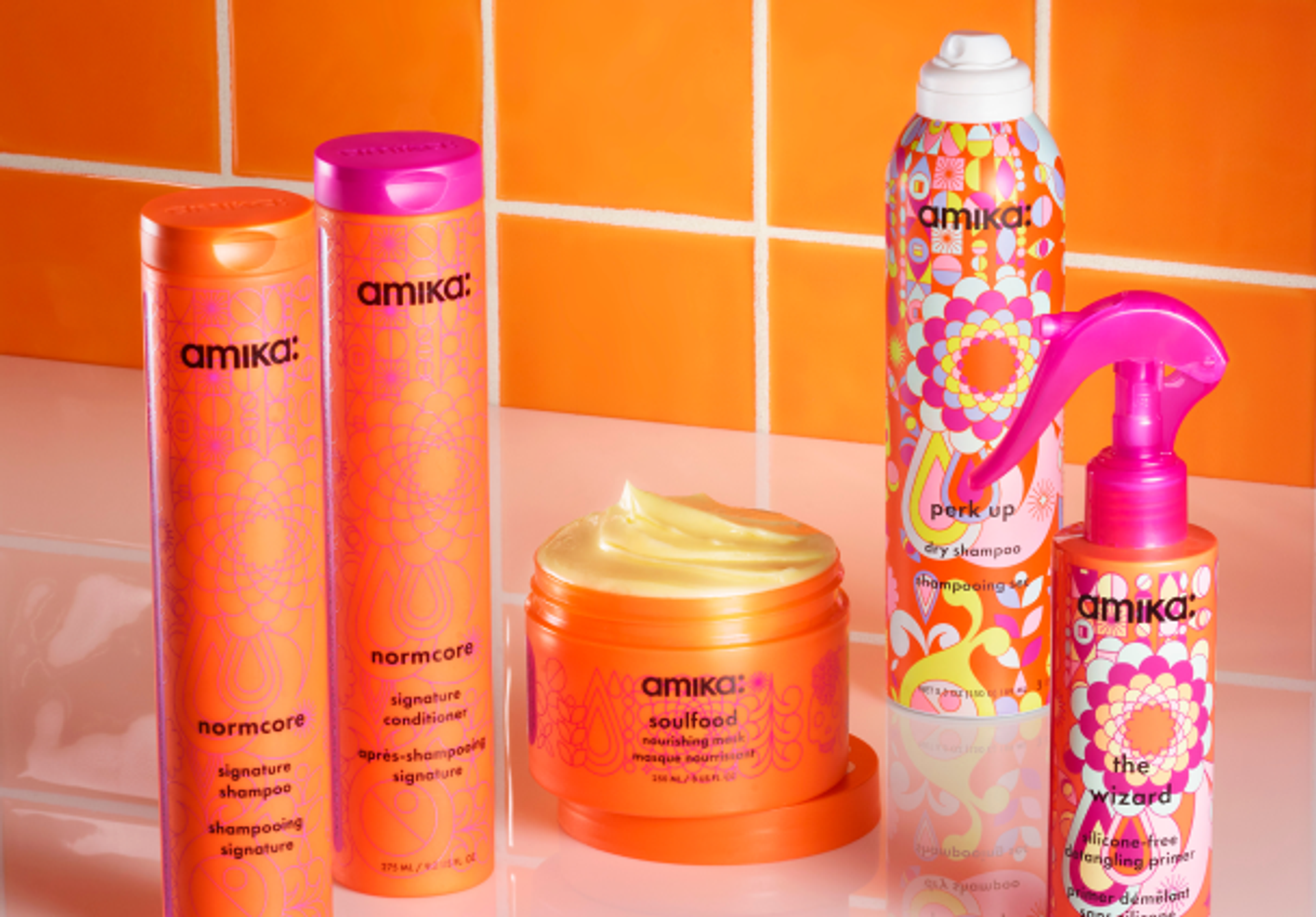 amika signature collection products on a white counter against an orange tiled background