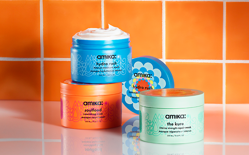 amika masks: hydro rush, soulfood, and the kure sit on a shiny white surface in front of an orange tiled background