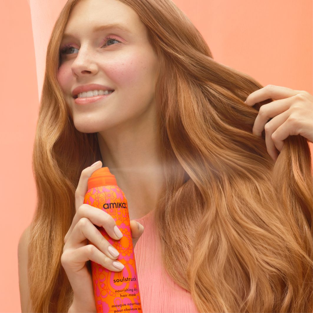 soulstruck model spraying product in front of a pinkish-orange background