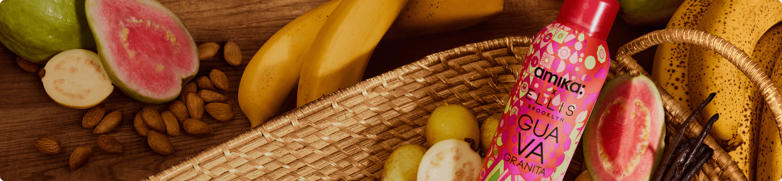 a bottle of amika perk up GUAVA GRANITA sits in a basket with guavas, bananas, and vanilla on a wooden background