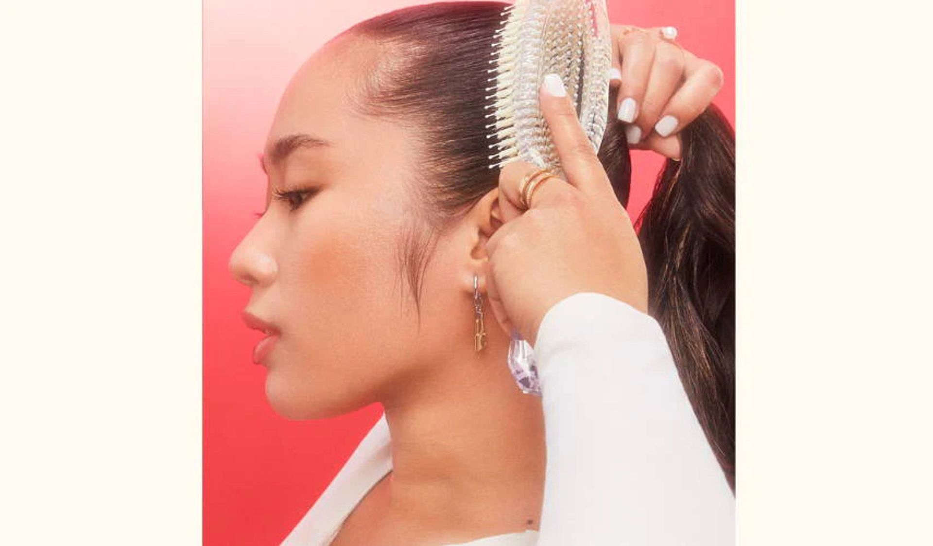 model brushing hair into a ponytail