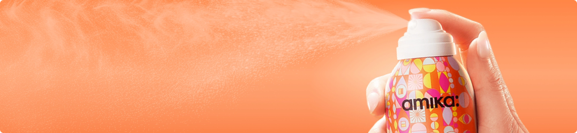 a bottle of amika dry shampoo spraying against an orange background