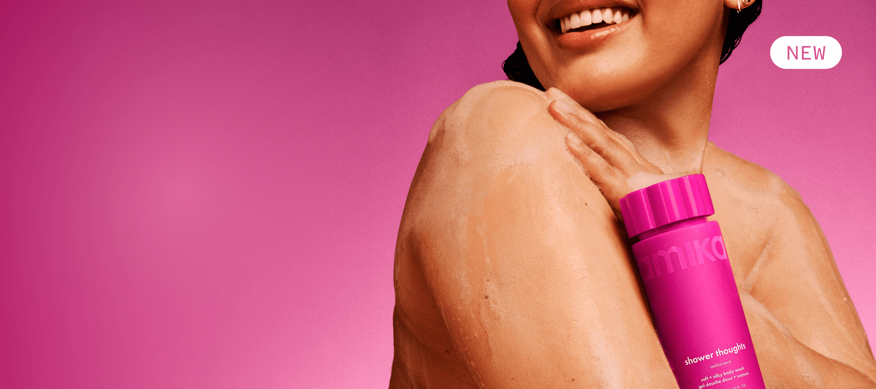 a model with lather on their skin holds amika shower thoughts against their chest. there is a pink background