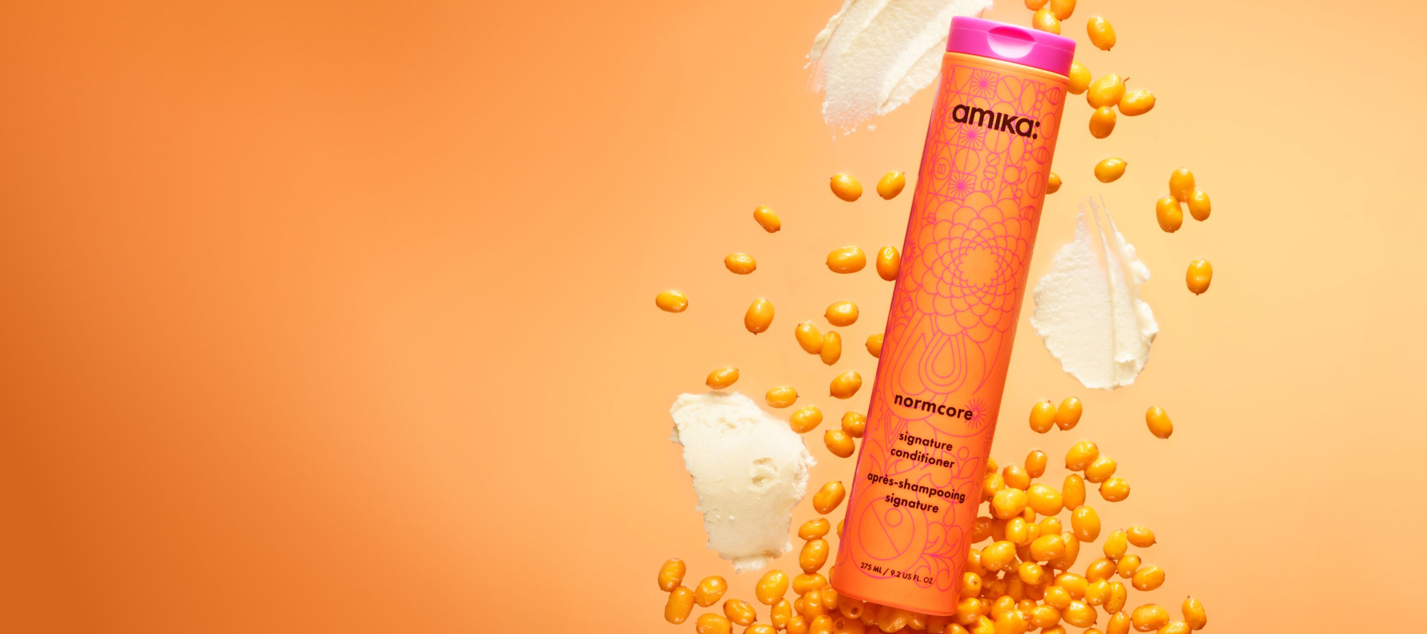 amika normcore signature conditioner surrounded by seabuckthorn and shea butter on an orange backgroundamika normcore signature conditioner surrounded by seabuckthorn and shea butter on an orange background