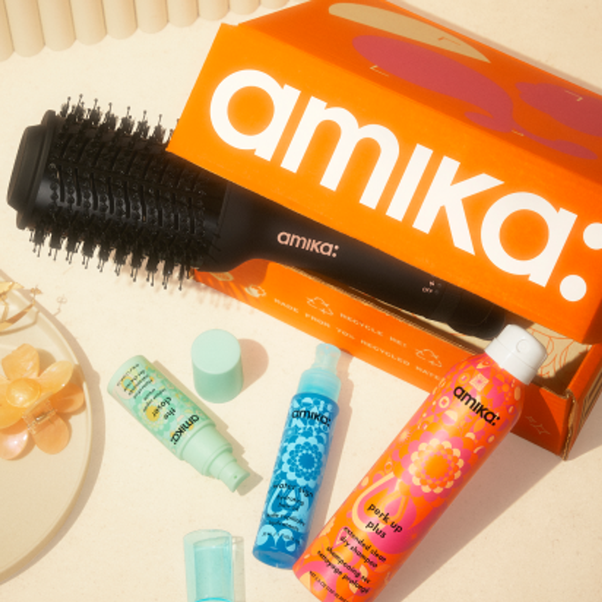 a collection of amika best selling products and an amika shipping box on a cream counter surface