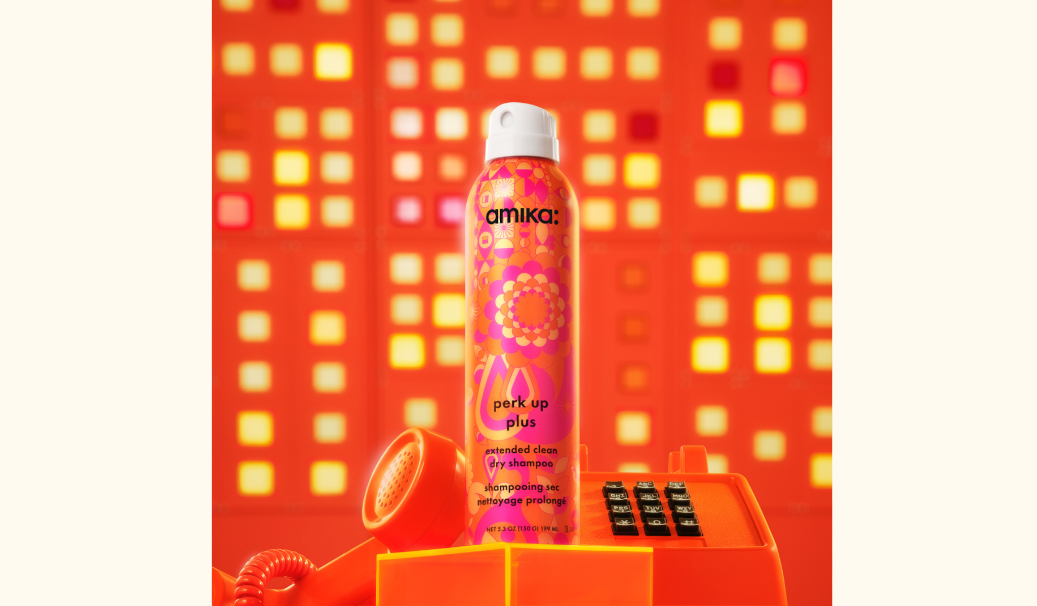 amika perk up plus extended clean dry shampoo spray bottle 5.3oz - pictured with an orange telephone against a geometric background