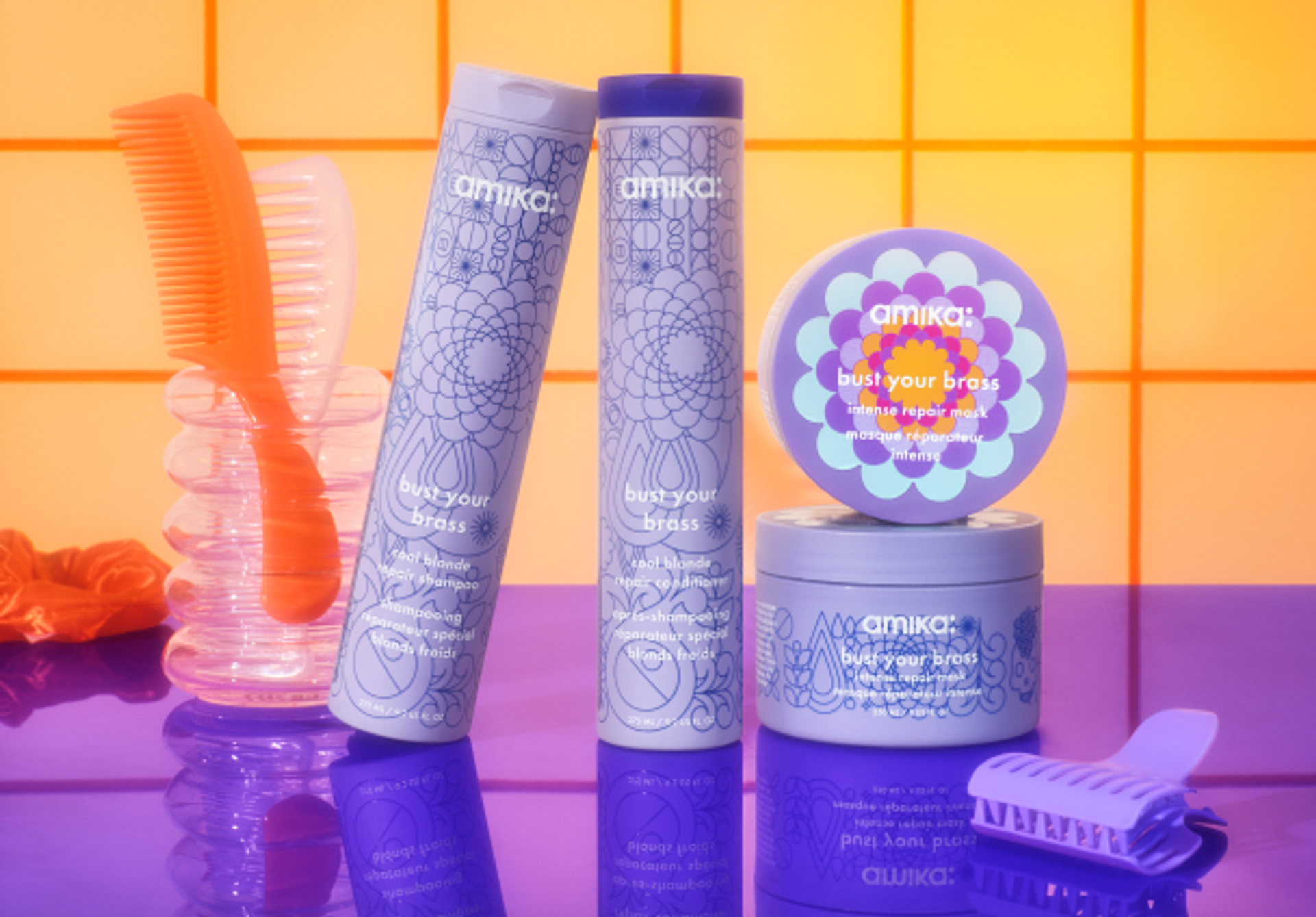 amika bust your brass cool blonde strength repair collection. products sit on a purple counter against a yellow tiled background