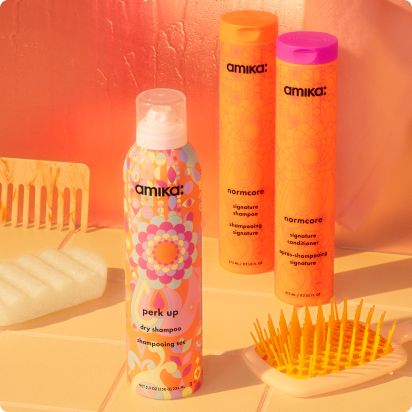 perk up dry shampoo and normcore shampoo and conditioner in front of orange background