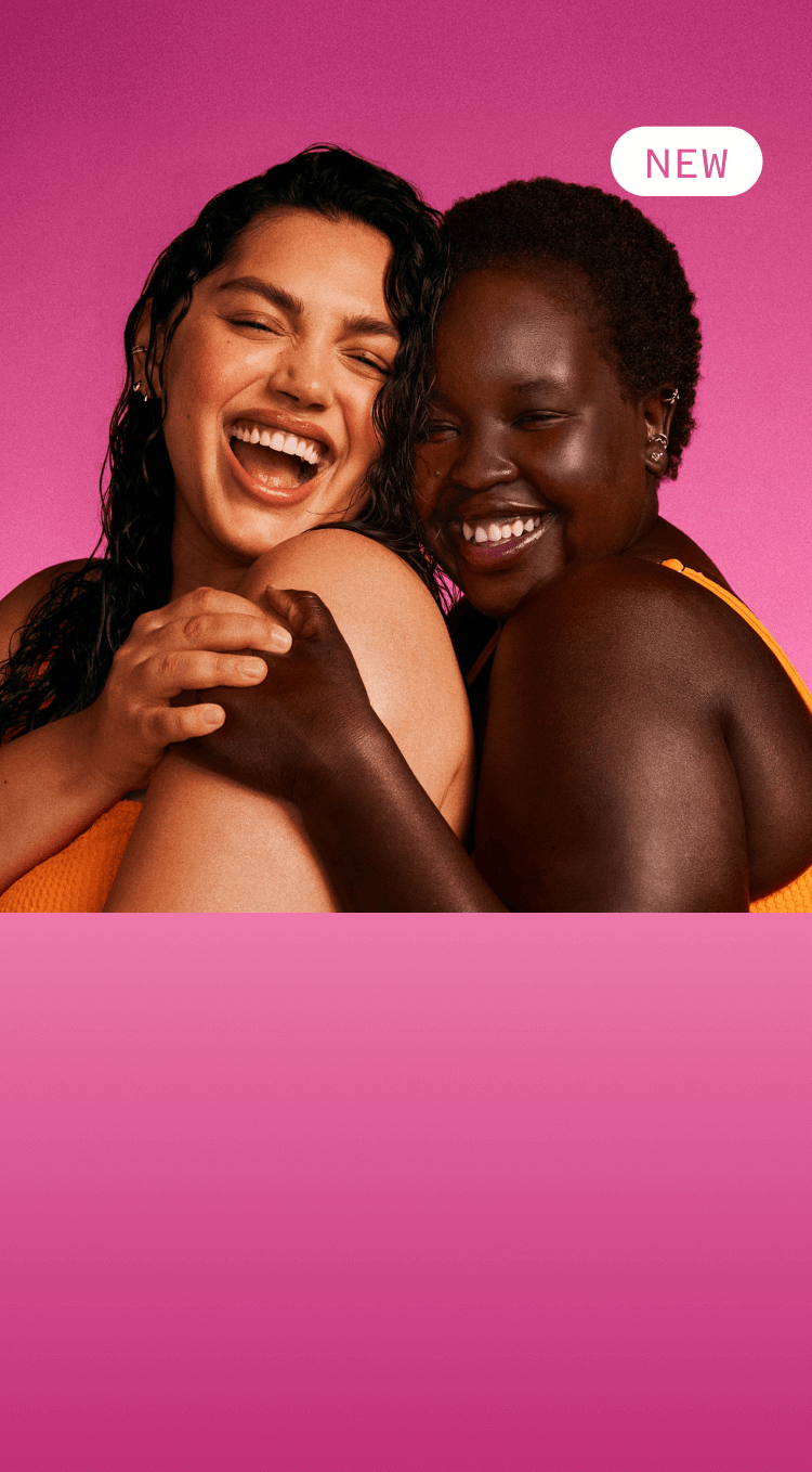 two models embrace with glowing skin in front of a pink background