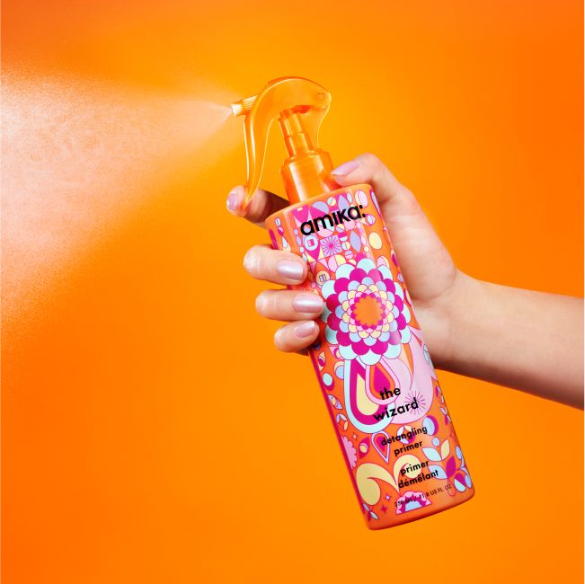 Image of a hand holding down the nozzle trigger on our NEW 11.8 oz jumbo wizard detangling spray.