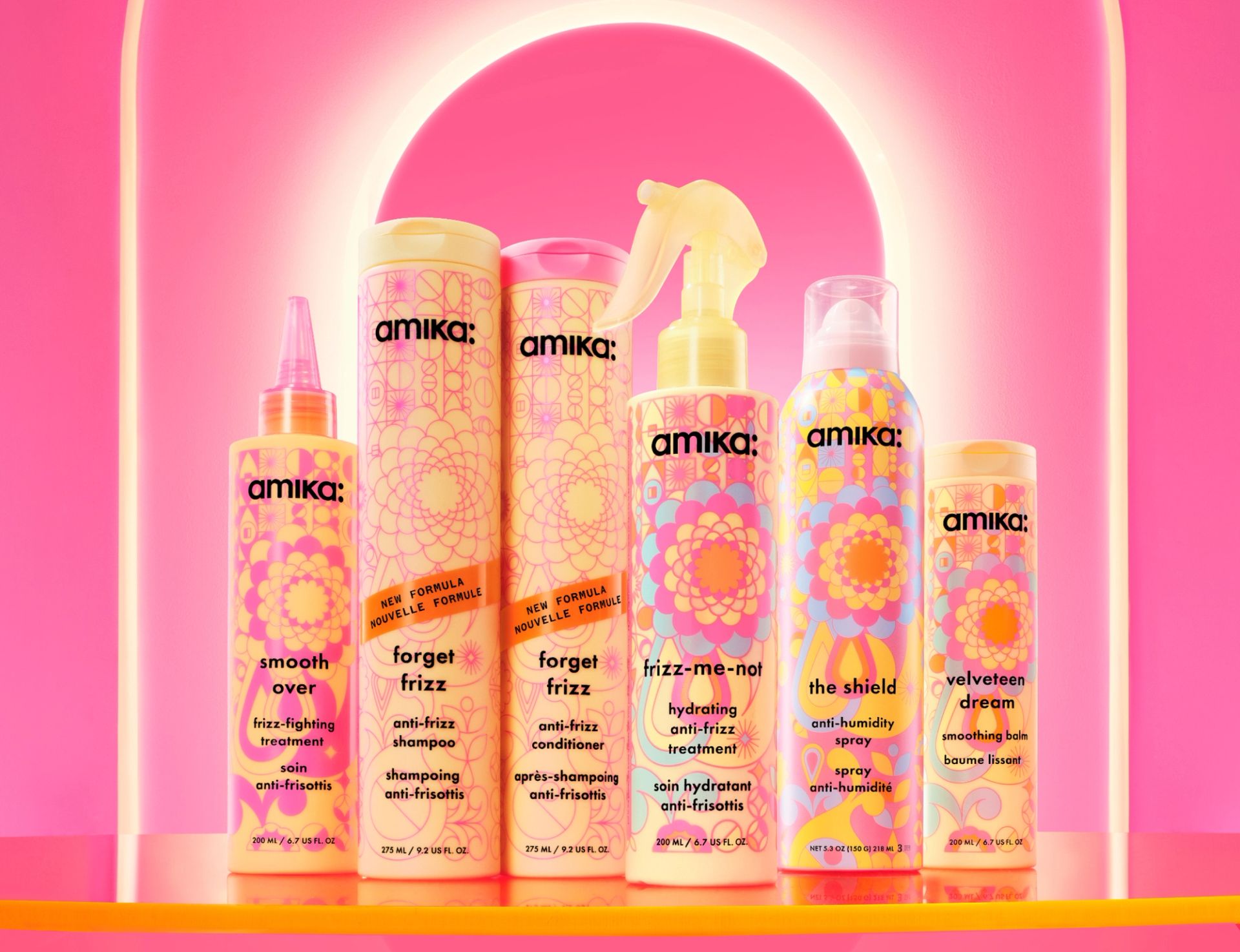 amika anti-frizz/ smoothing collection products in front of a pink illuminated background