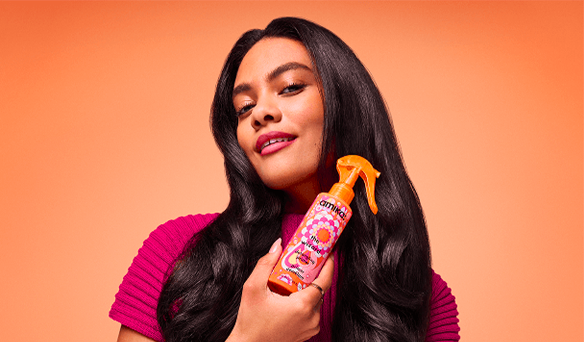 a model holds a bottle of amika the wizard detangling primer
