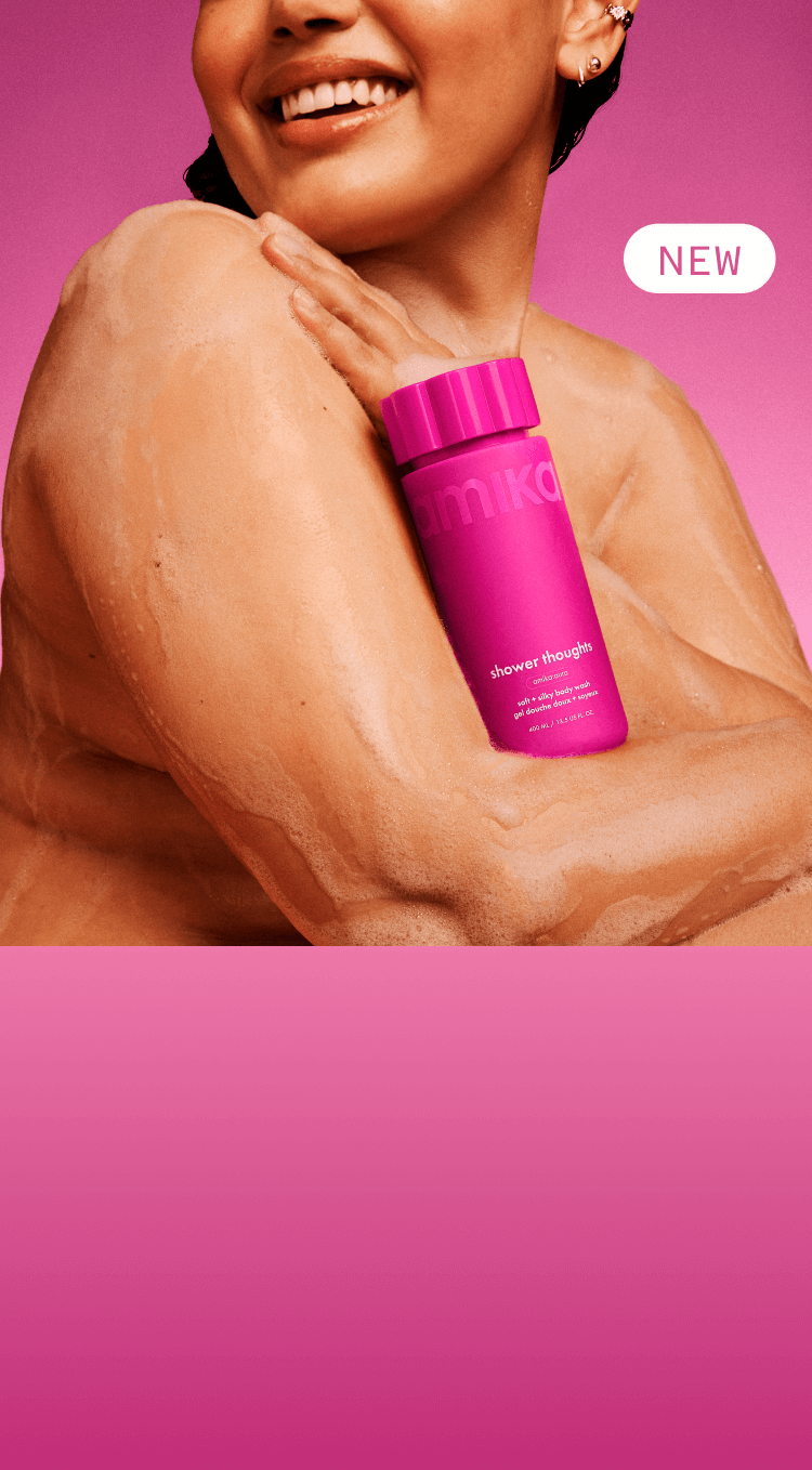 a model with lather on their skin holds amika shower thoughts against their chest. there is a pink background