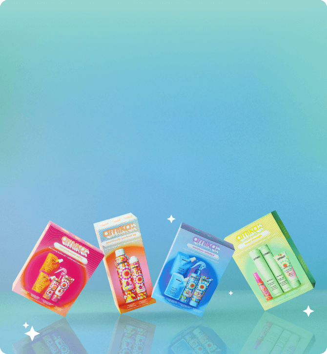 amika holiday gift sets are arranged playfully against a blue gradient background