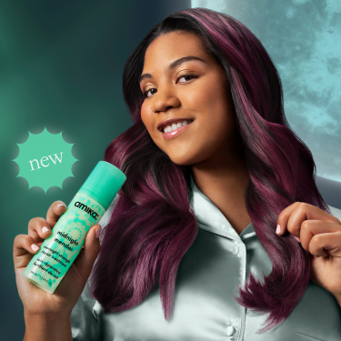 a model with long, shiny hair poses with amika's new midnight mender overnight strength repair treatment