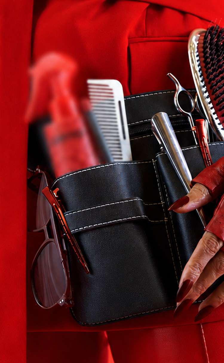 a closeup of a hairstylist's tool belt with scissors, comb, brush, and a blurred-out product. the person is wearing all red.