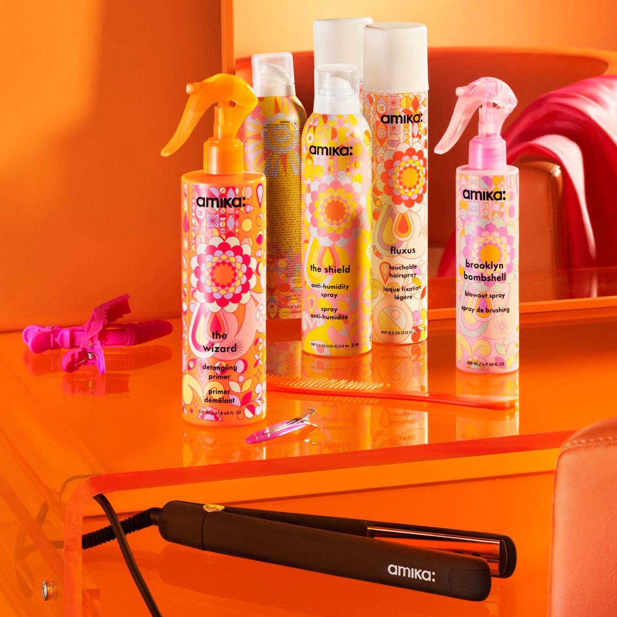 amika hair straightener, the wizard detangling primer, the shield, fluxus and brooklyn bombshell spray on an orange table