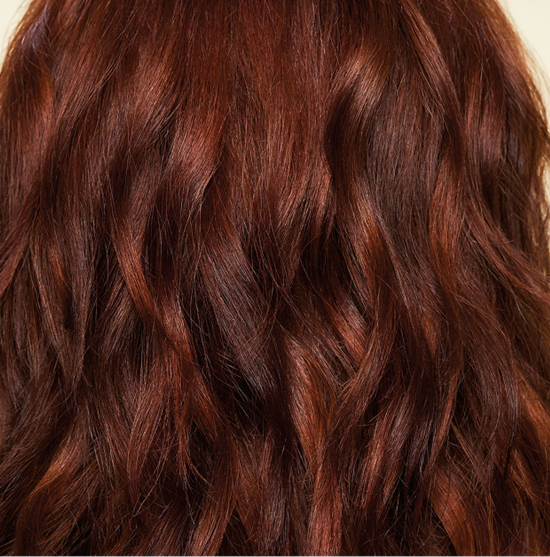 back of a model's smooth, shiny, red, wavy hair