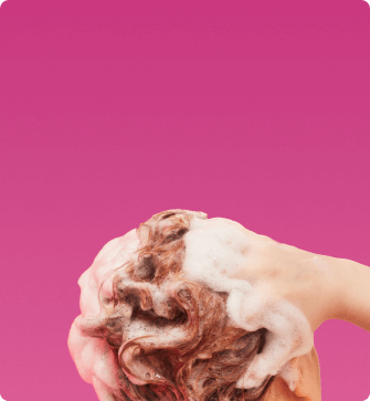a model lathers their hair against a pink background