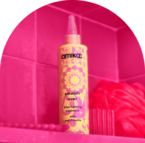 bottle of amika smooth over frizz-fighting treatment in a pink shower