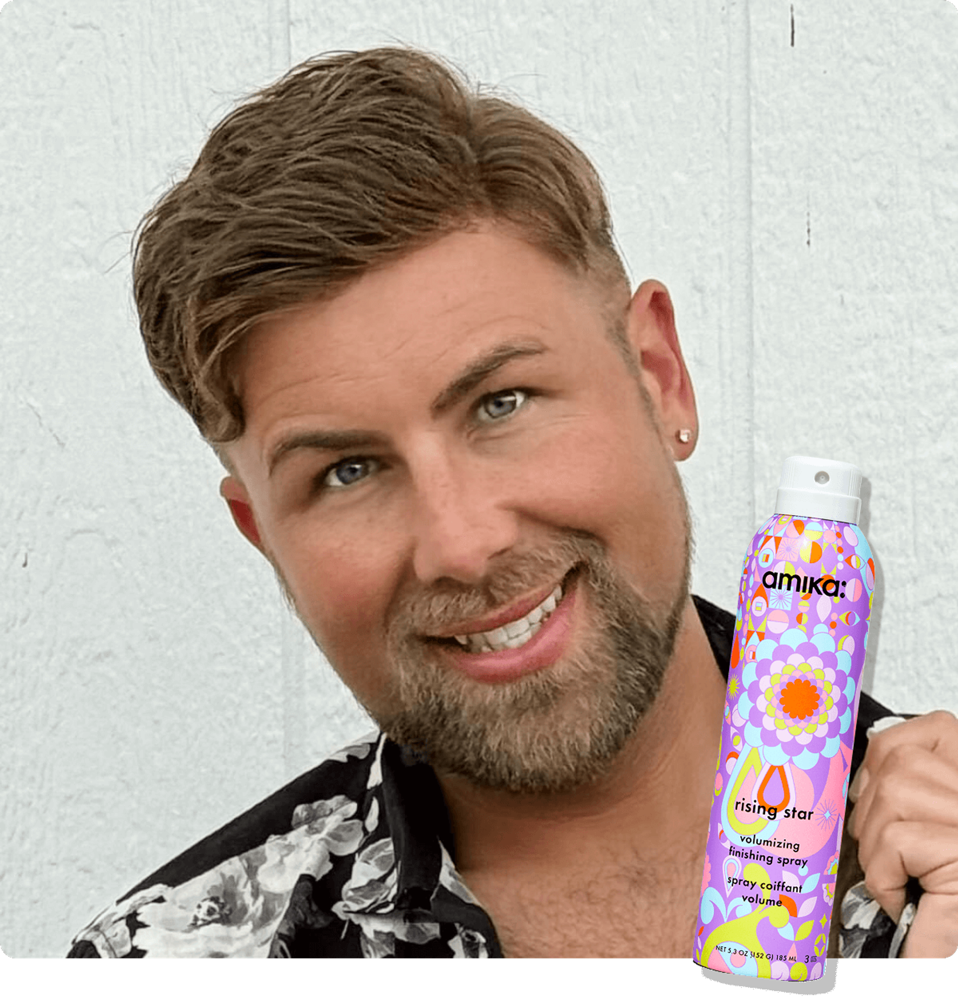 amika Brand Educator Derek Viers poses smiling. A sticker of amika rising star finishing spray appears in the bottom right corner.