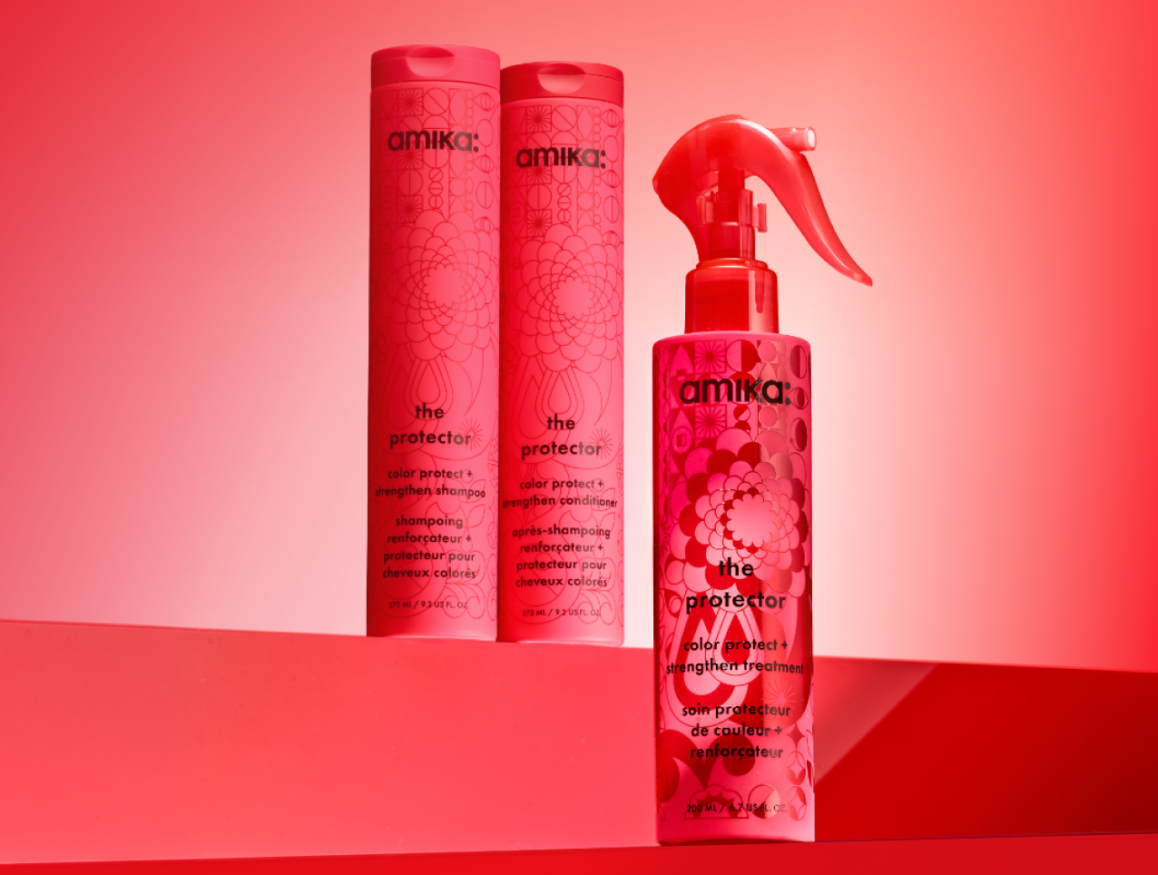 bottles of amika's the protector shampoo, conditioner, and treatment sit against a red gradient background