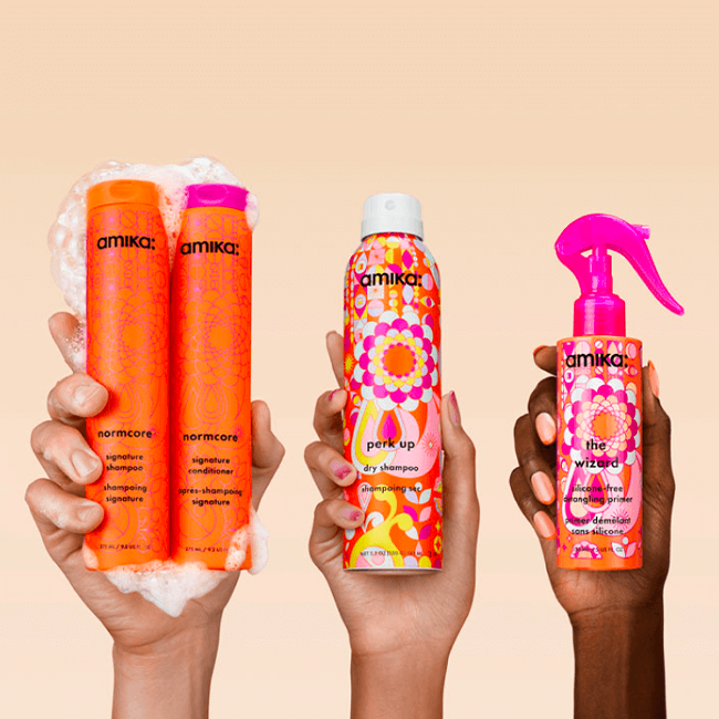 three hands hold up amika products against a cream background