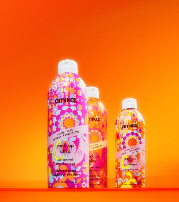 amika dry shampoos sit against an orange backdrop: perk up ultra, perk up plus, and perk up - all in jumbo value size: 9.5 oz