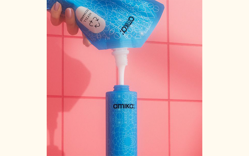 hand pouring refill shampoo pouch into bottle