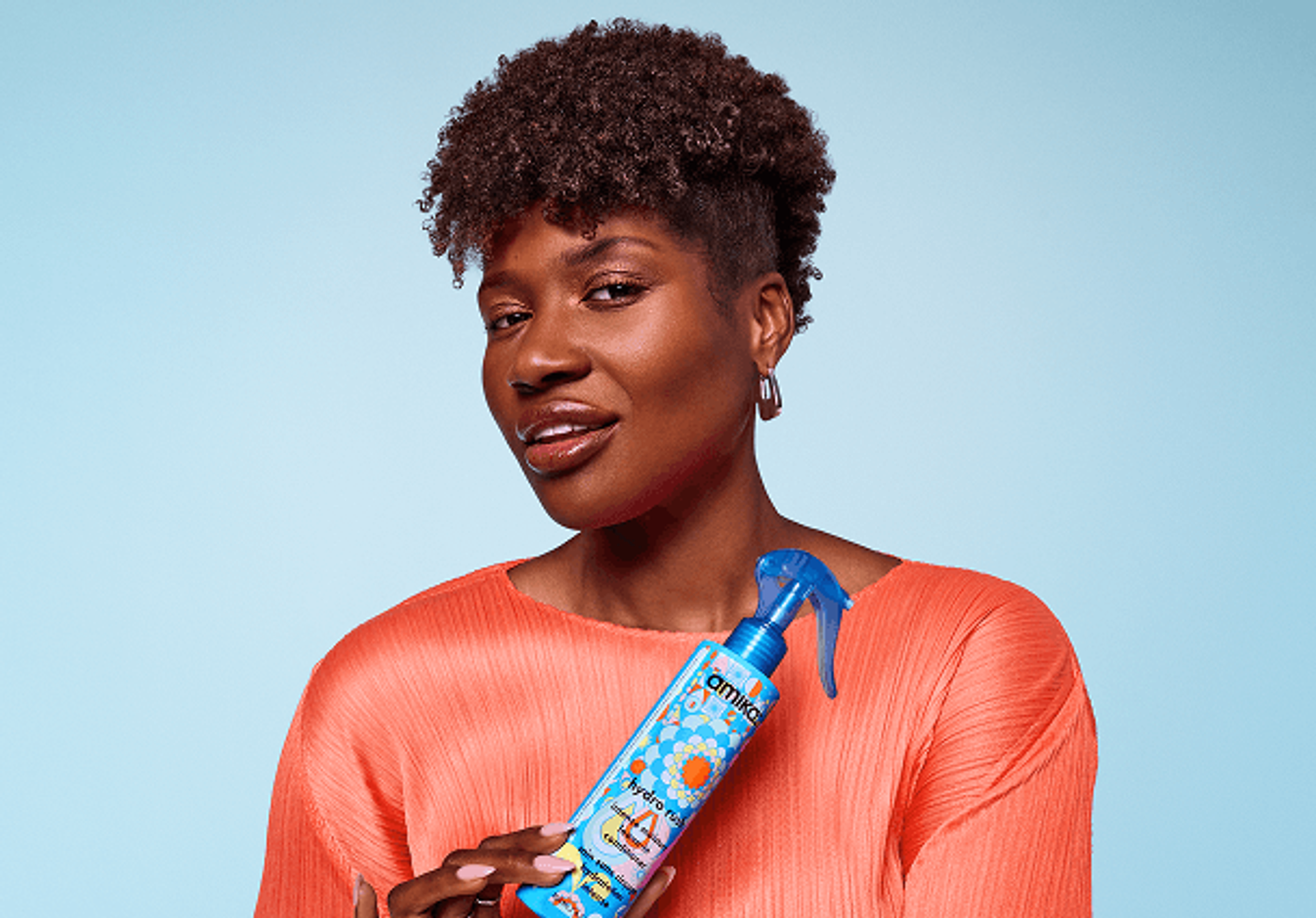 a model holds a bottle of amika hydro rush leave-in conditioner