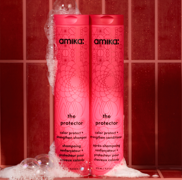 amika the protector shampoo and conditioner bottles in a red shower setting