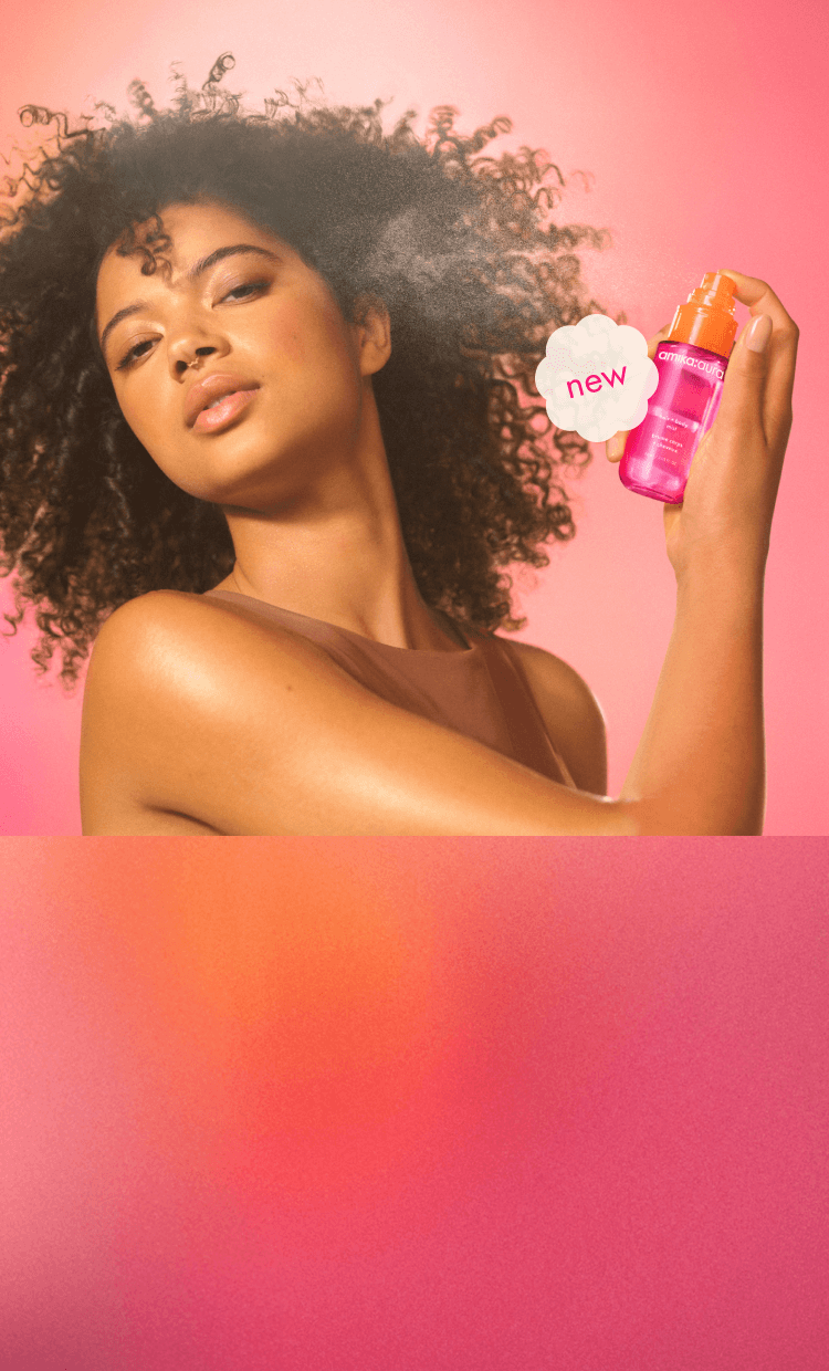 image of a model using aura mist on their skin against a pink orange gradient background.