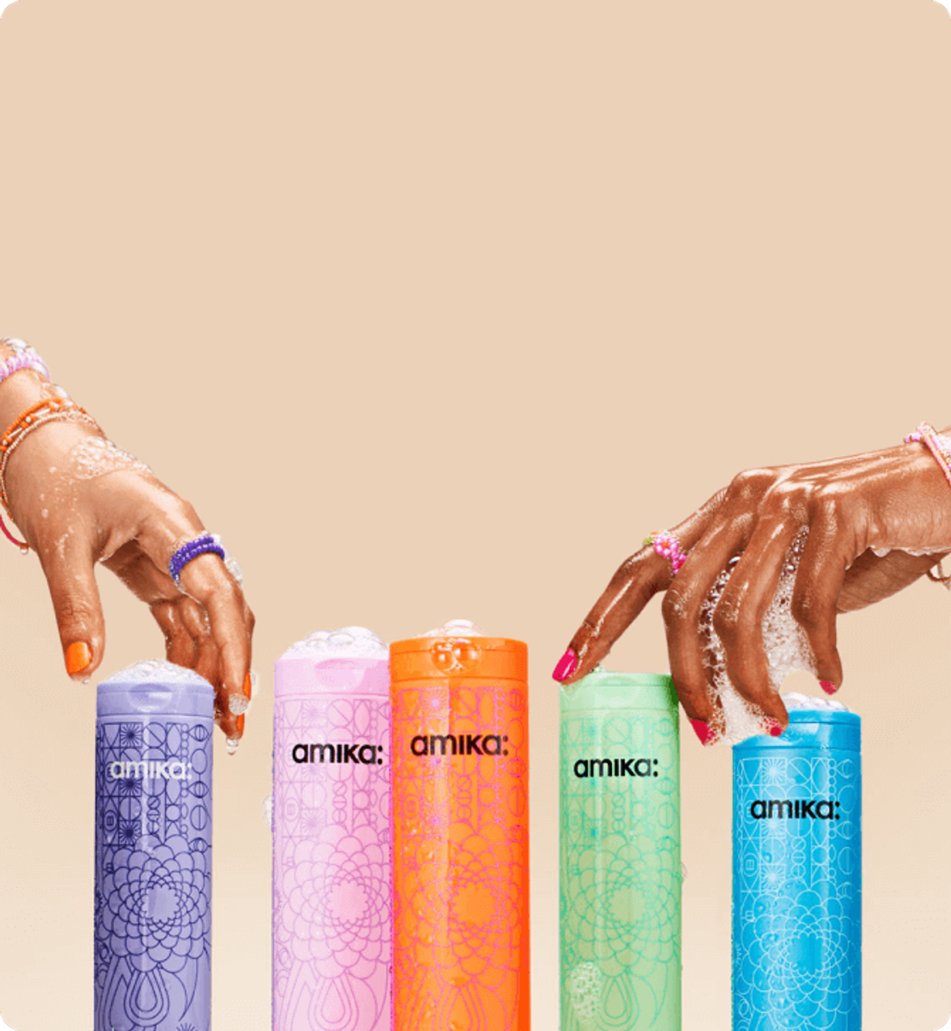 two hands with soapy lather on them reach for amika shampoo bottles against a cream background