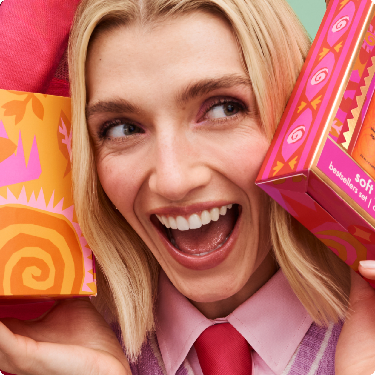 a blonde model smiles joyfully while holding colorful gift boxes
