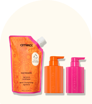 image of amika refill bundle, normcore refill pouch and one pink and one orange refillable bottles sit against a cream background.