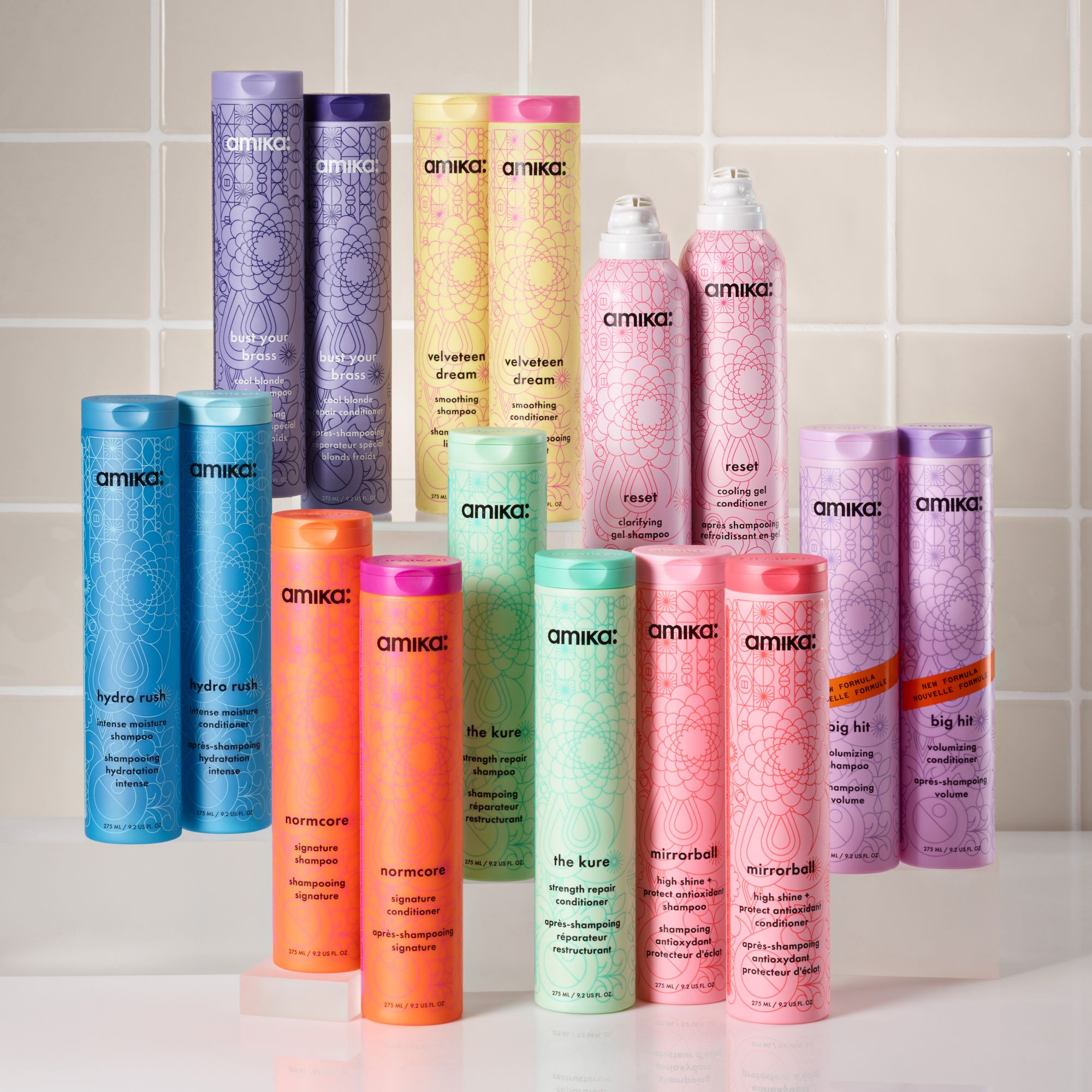 full assortment of amika shampoos and conditioners against a light gray tiled background