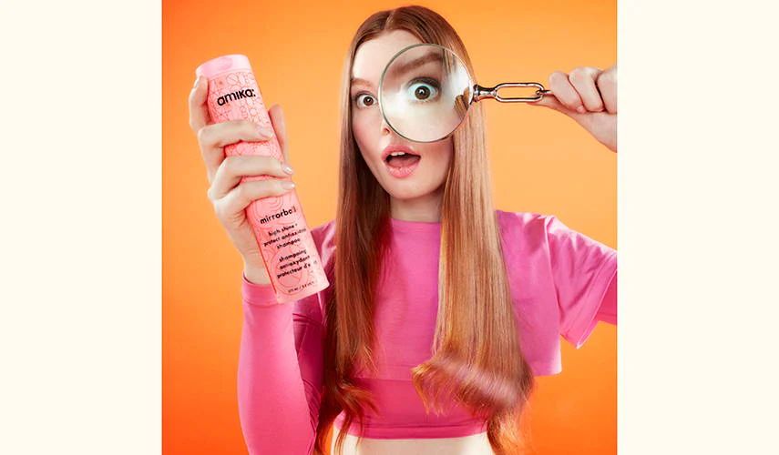 model holding magnifying glass and mirrorball shampoo