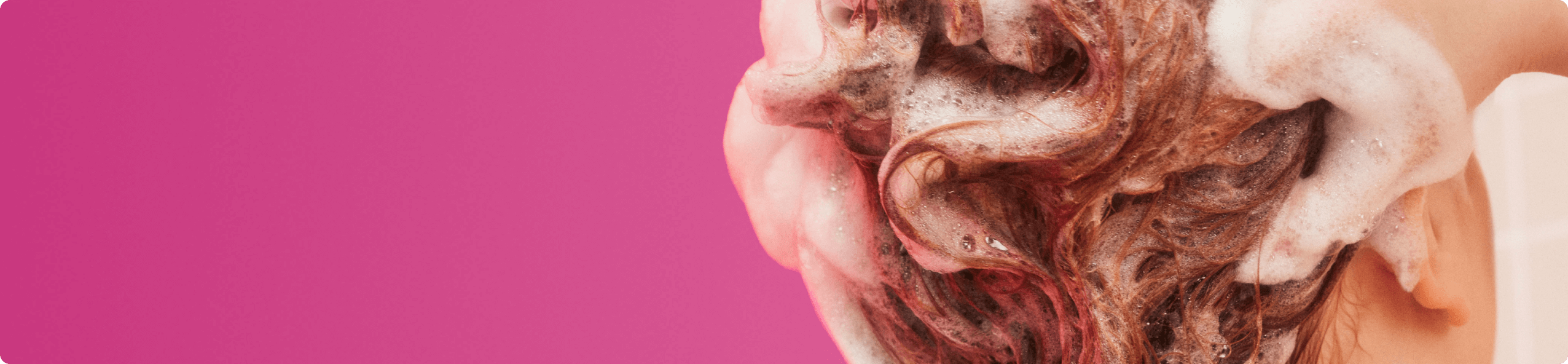 a model lathers their hair against a pink background