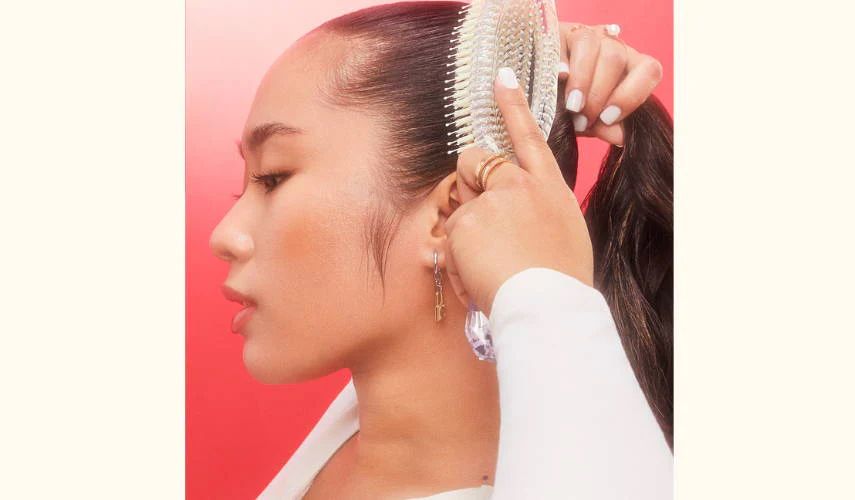 model brushing hair into ponytail